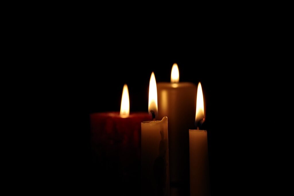 Cluster of 4 lit candles in the dark