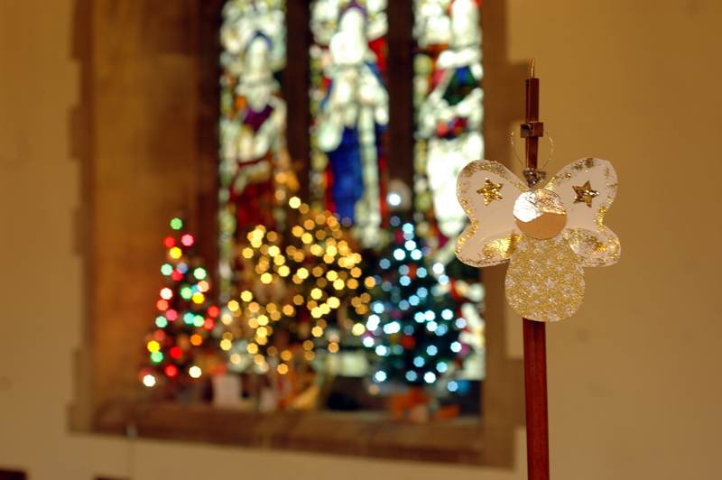 Cardboard angel and soft focus Christmas Trees on the windowsill