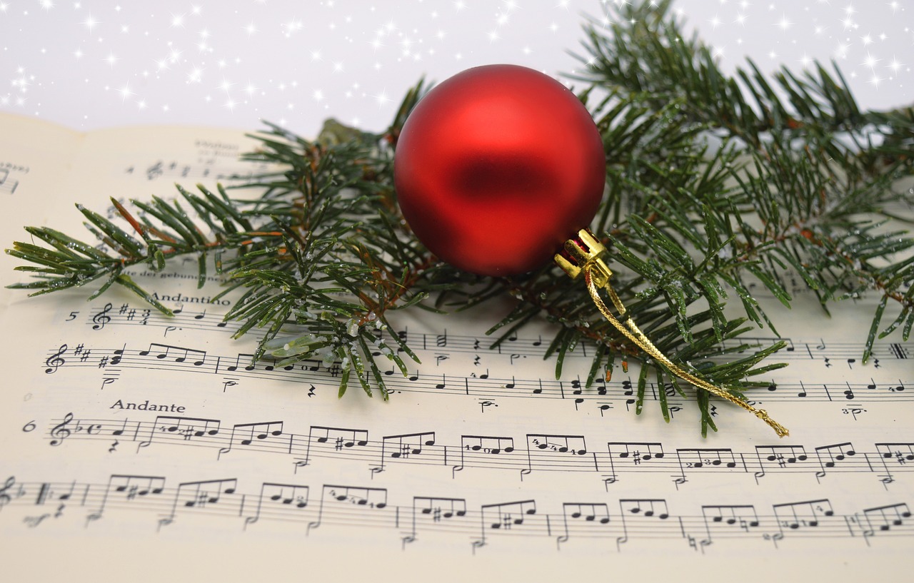 Red Bauble and green tree branch sitting on sheet music