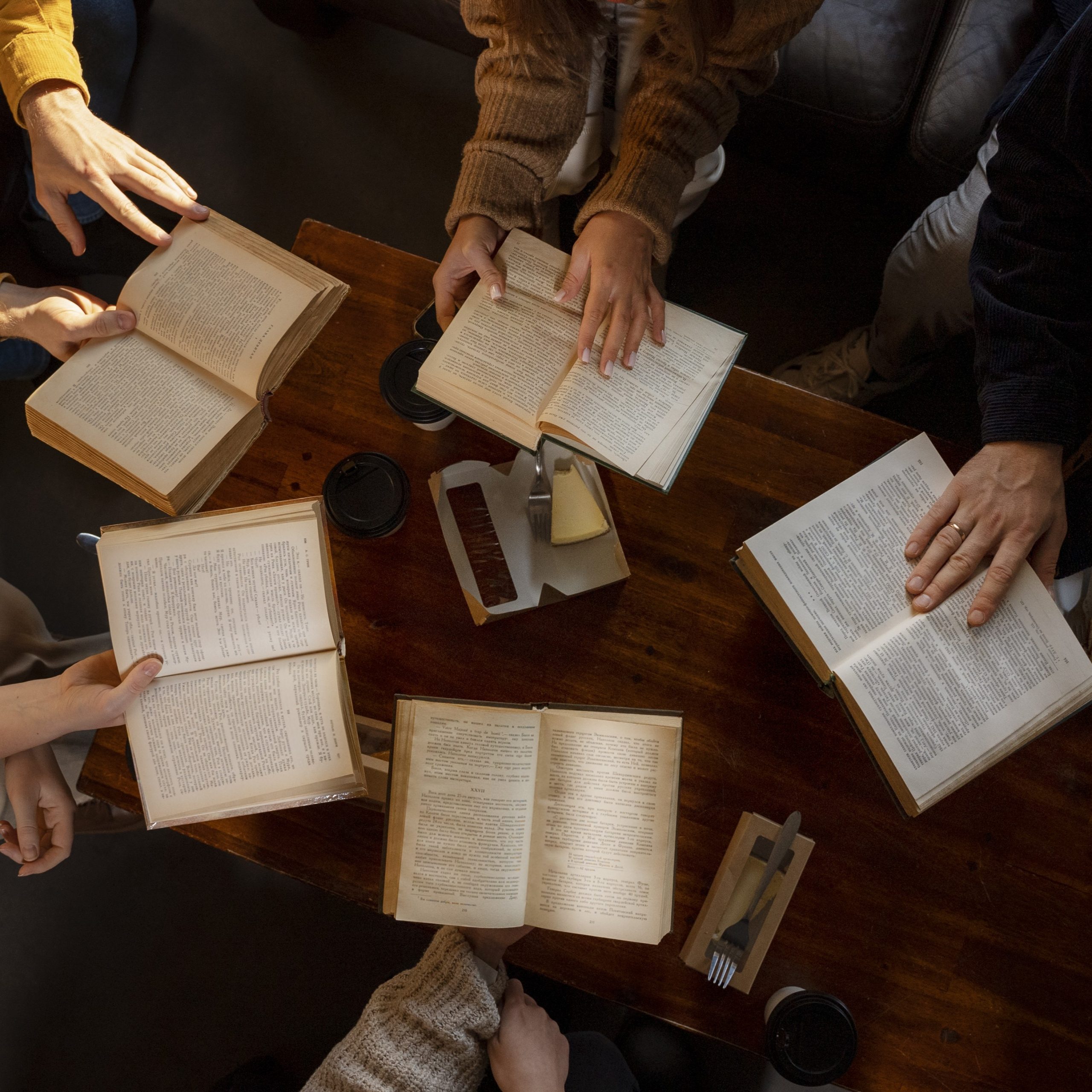 Hands and bibles around a table. View from above.